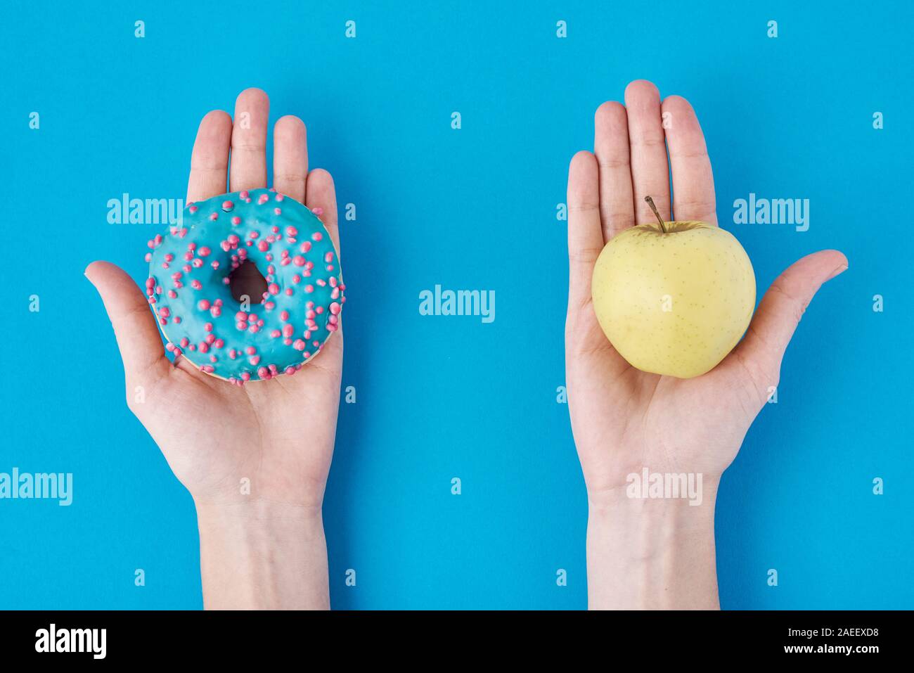 Woman choosing betwen apple and donut in her hands. Healthy food concept. Stock Photo