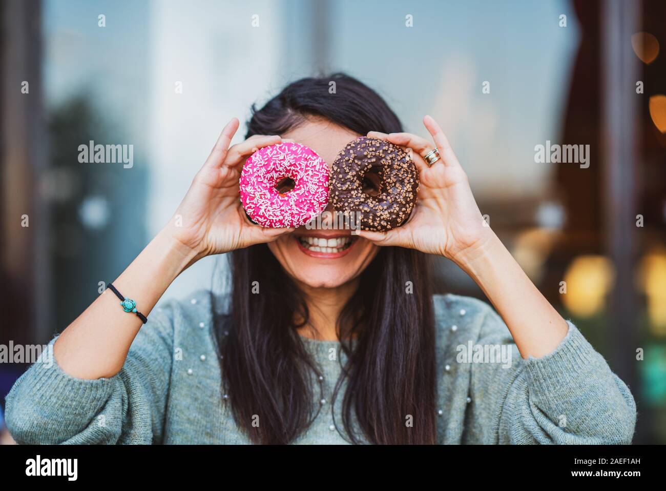 Woman is holding delicious and colored donuts with humor. Stock Photo