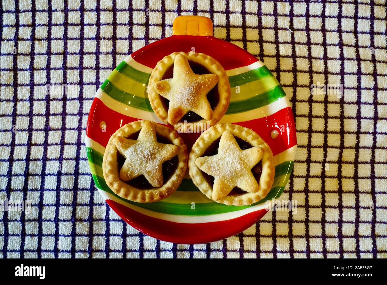 Three home made mince pies with an icing sugar dusting on a festive ...