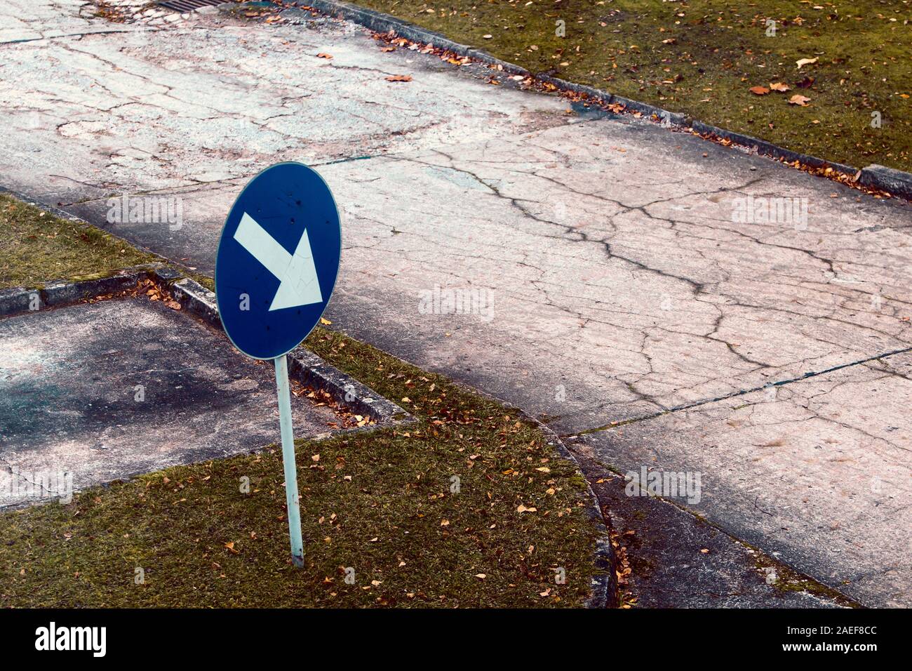 Arrow sign to an empty road in bad condition. Emphasis on transport infrastructure, transport policy, neglect and upkeep. Stock Photo