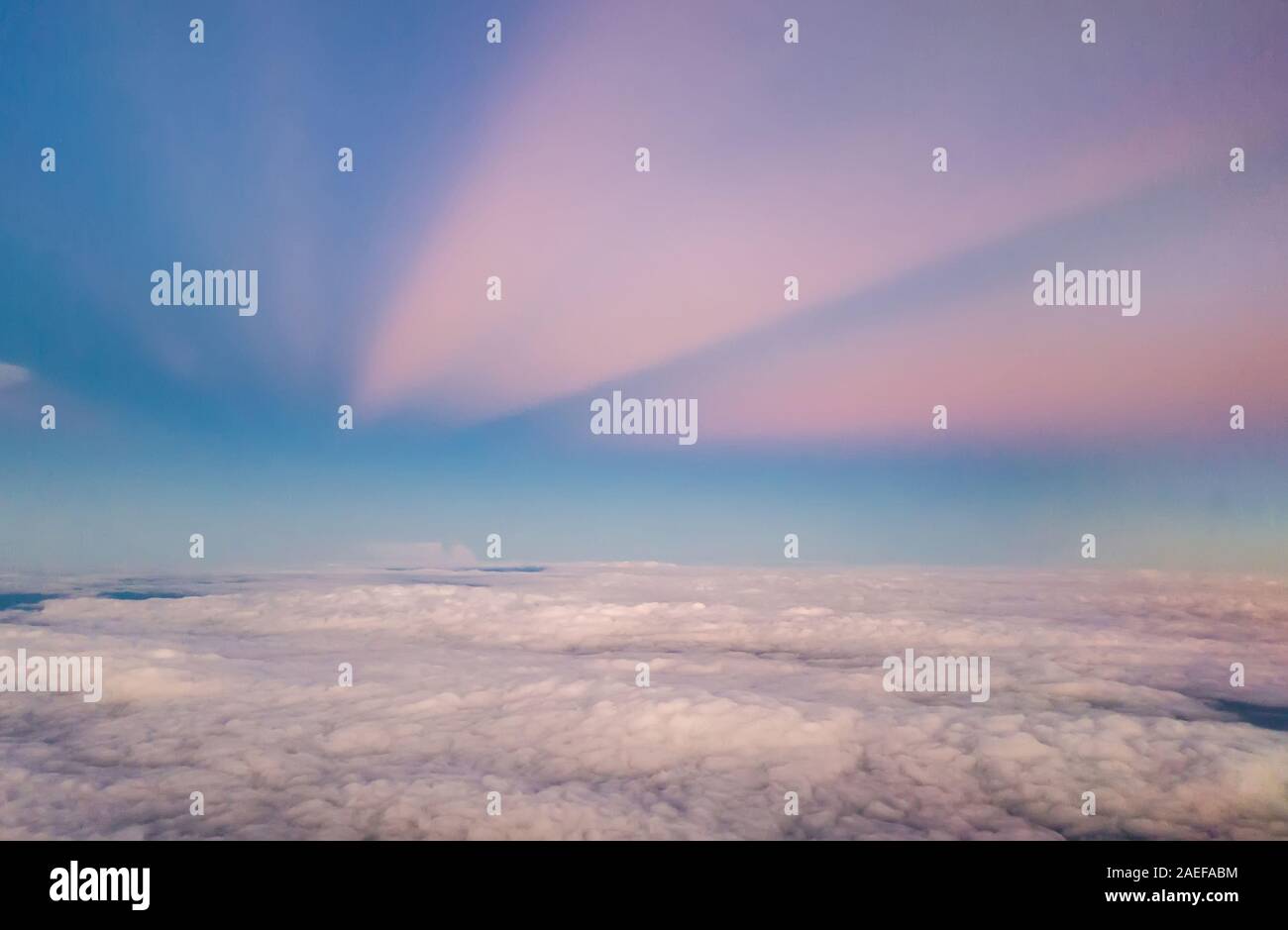beautiful pastel sky atmosphere over white puffy cloud before sunset as seen through window of airplane, plane window. travel by airplane Stock Photo