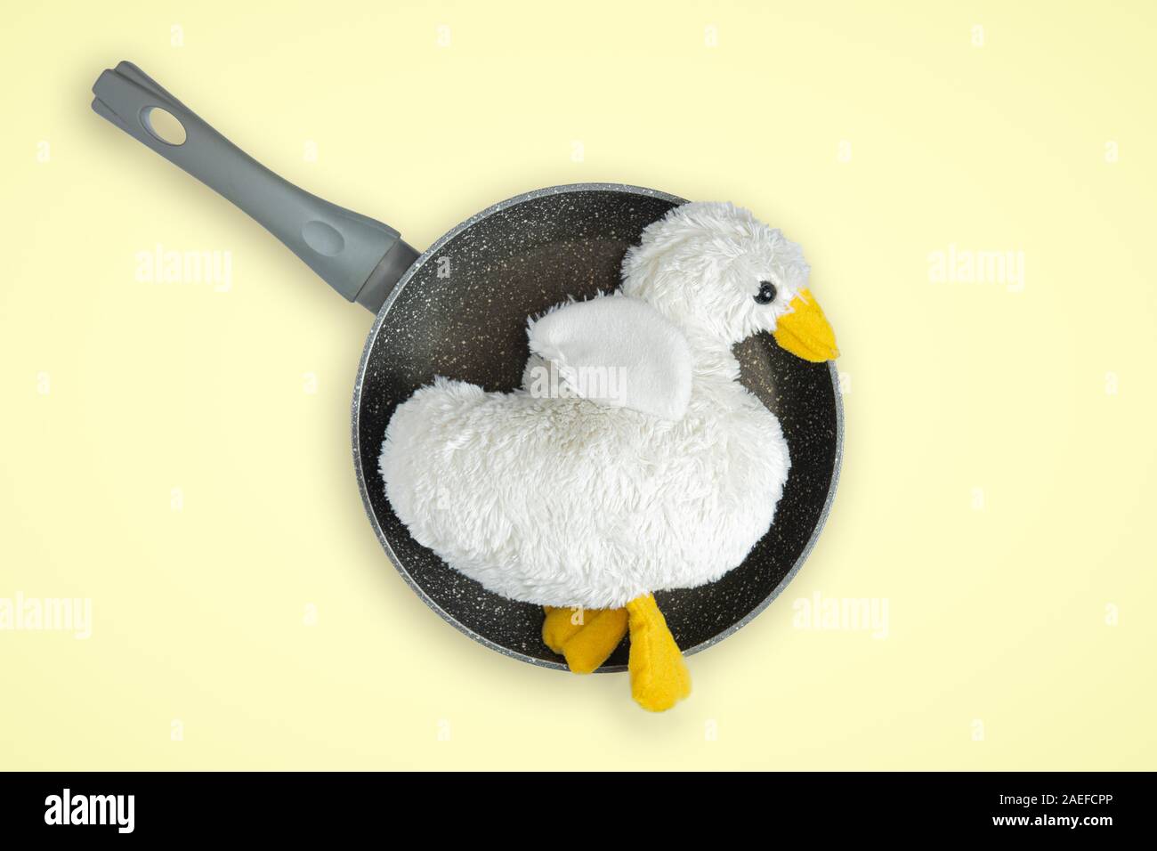 Fluffy toy bird on a frying pan, top view. Meat industry, poultry consumption concept Stock Photo
