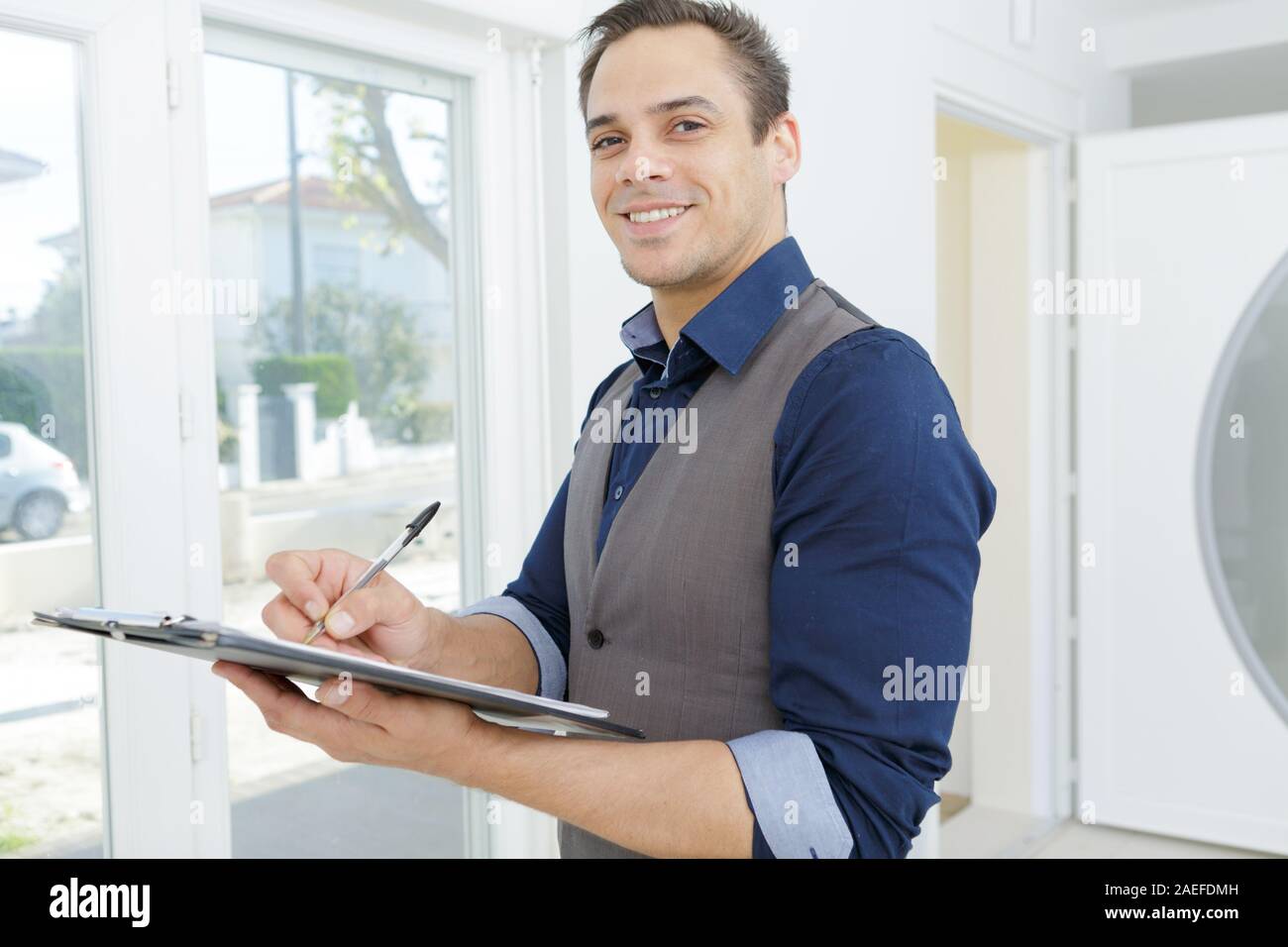 smiling young lead worker taking notes on his clipboard Stock Photo - Alamy