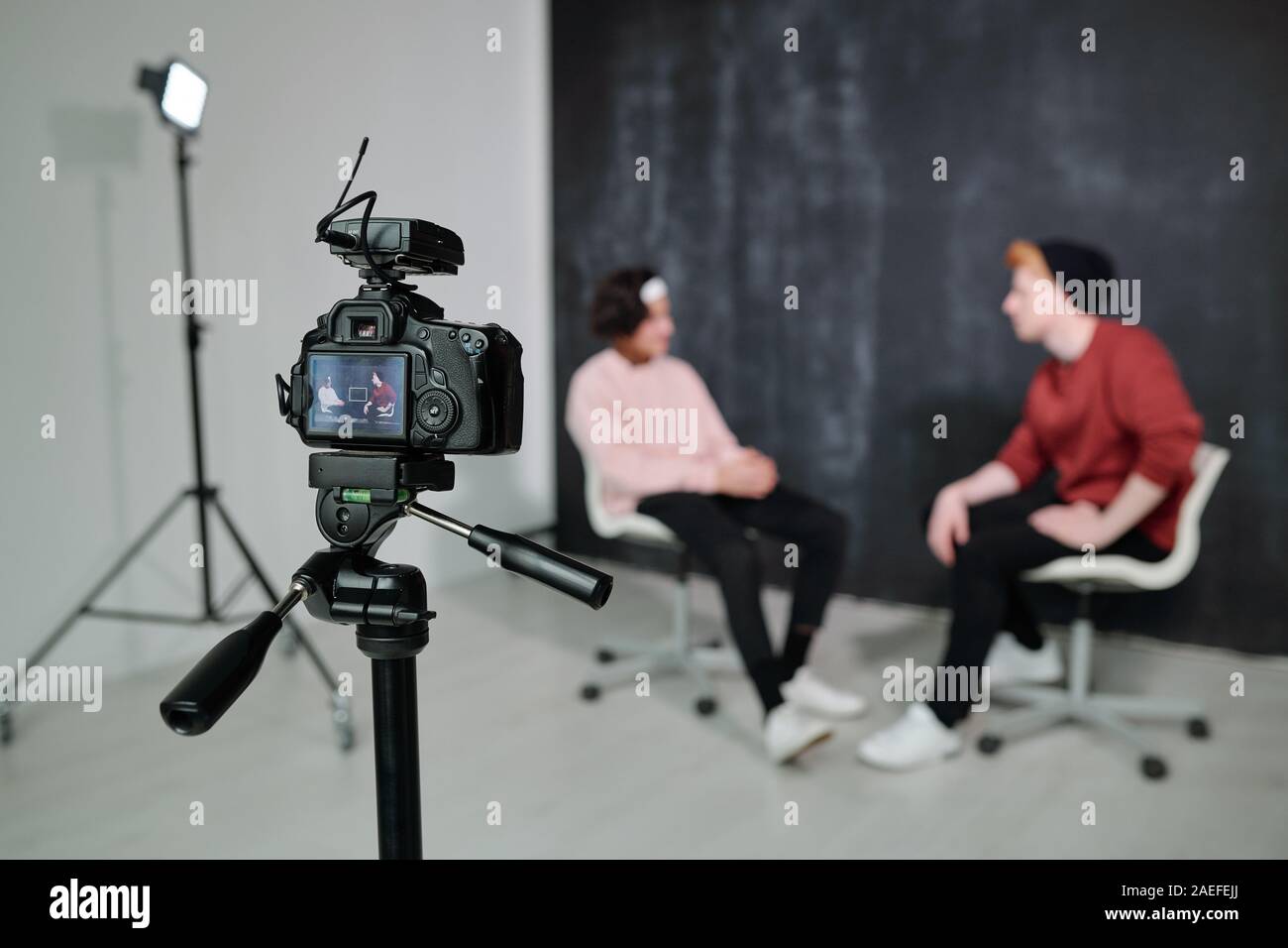 Screen of digital video camera with two vloggers having conversation in studio Stock Photo