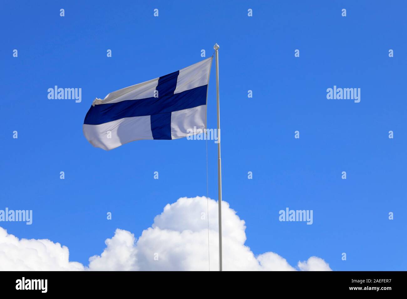 National Flag of Finland flying against blue sky and white clouds. Stock Photo