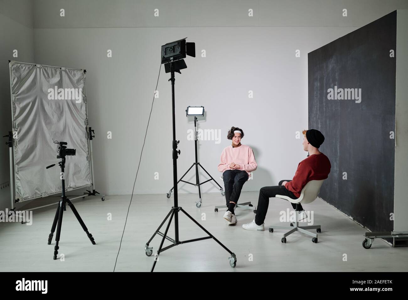 Two young friendly vloggers discussing contemporary fashion trends in studio Stock Photo