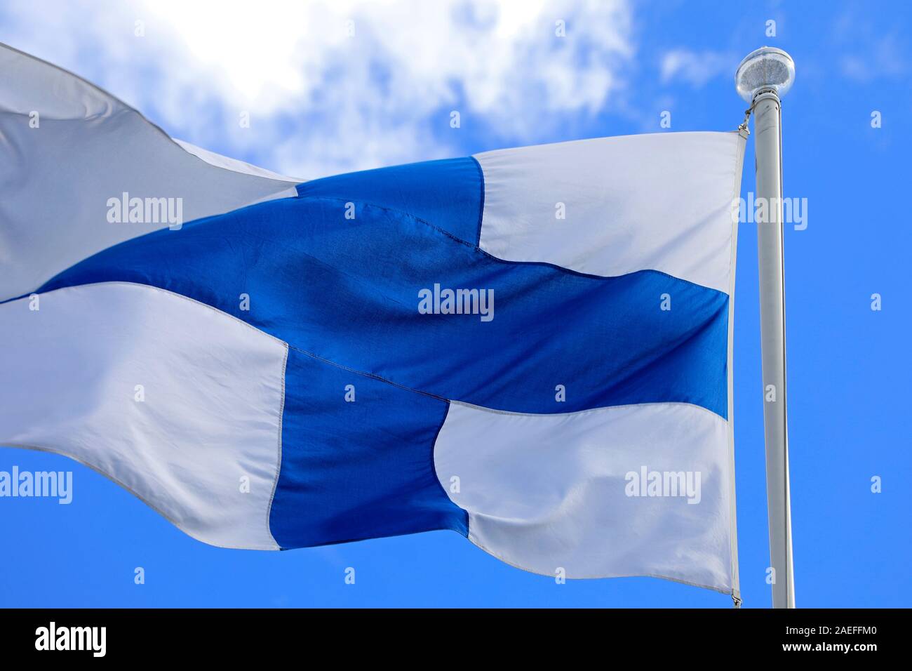 National Flag of Finland in motion flying against blue sky and white clouds. Stock Photo
