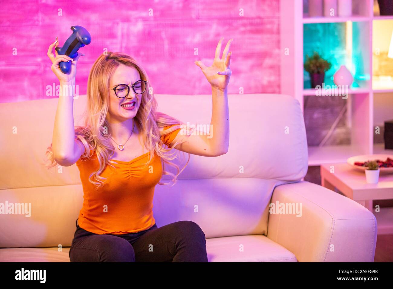 Man beating woman at video games with controller on console over blue  background. Boyfriend celebrating win and girlfriend feeling disappointed  about losing online gameplay in studio Stock Photo - Alamy