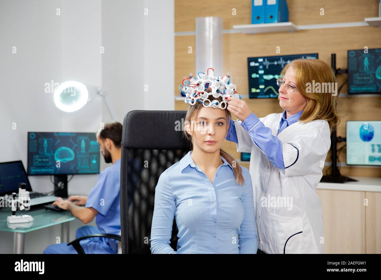 Doctor arranging brain waves scanning headset for a patient. Neurology lab and scanning device Stock Photo