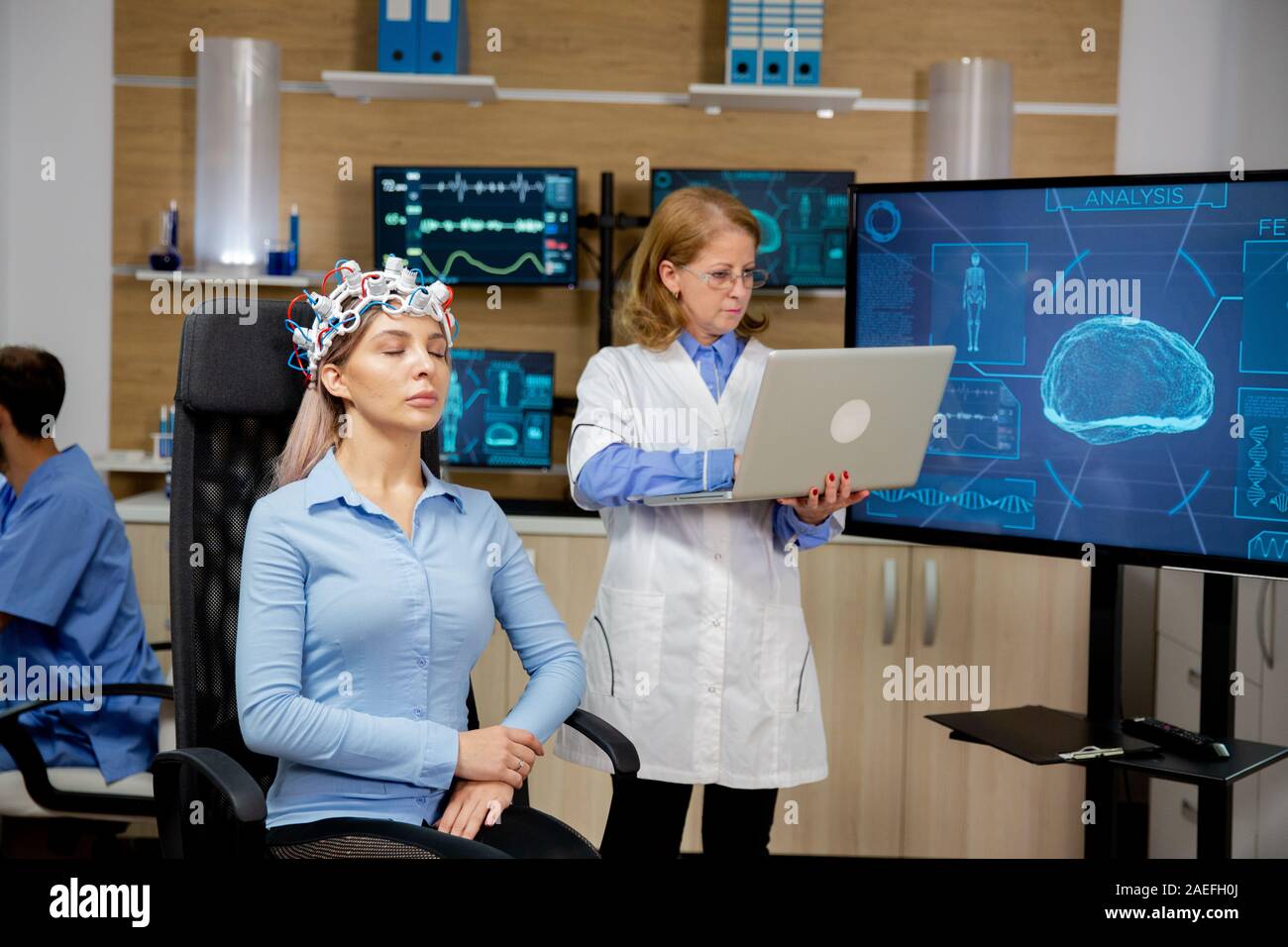 Doctor analyzing live data on a laptop during a girl's brain scan procedure. Brain waves scanning device Stock Photo