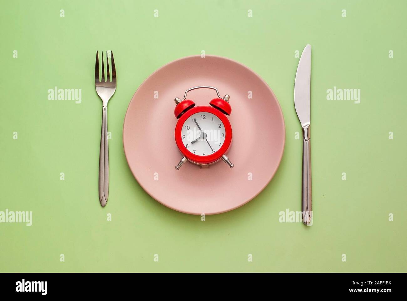 Red alarm clock on a clean pink plate Stock Photo