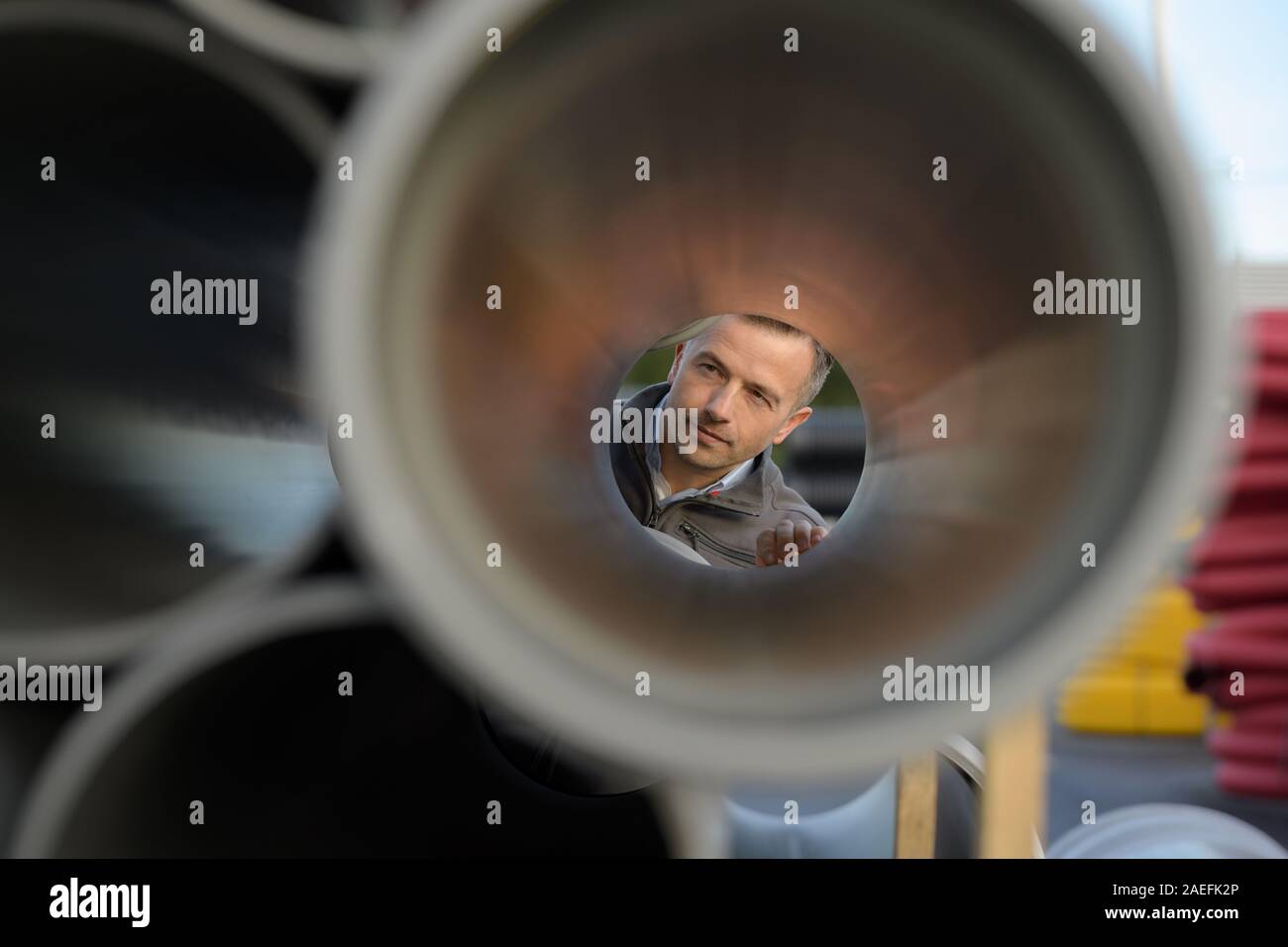 man looking through a plastic drain spout Stock Photo - Alamy