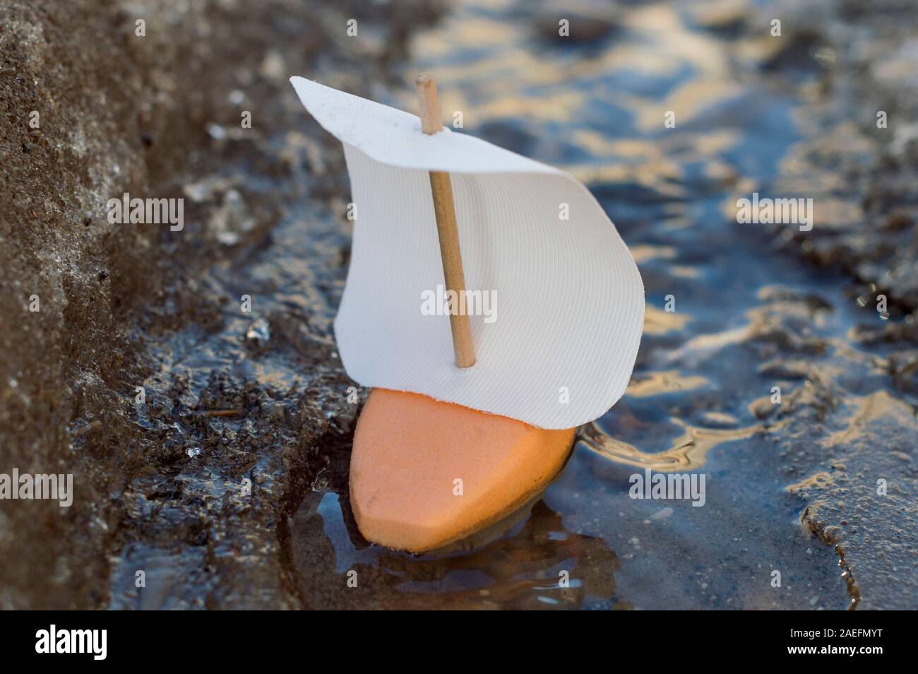 A small foam boat floats on a spring stream and the glint of the sun play on it. Close-up. Stock Photo