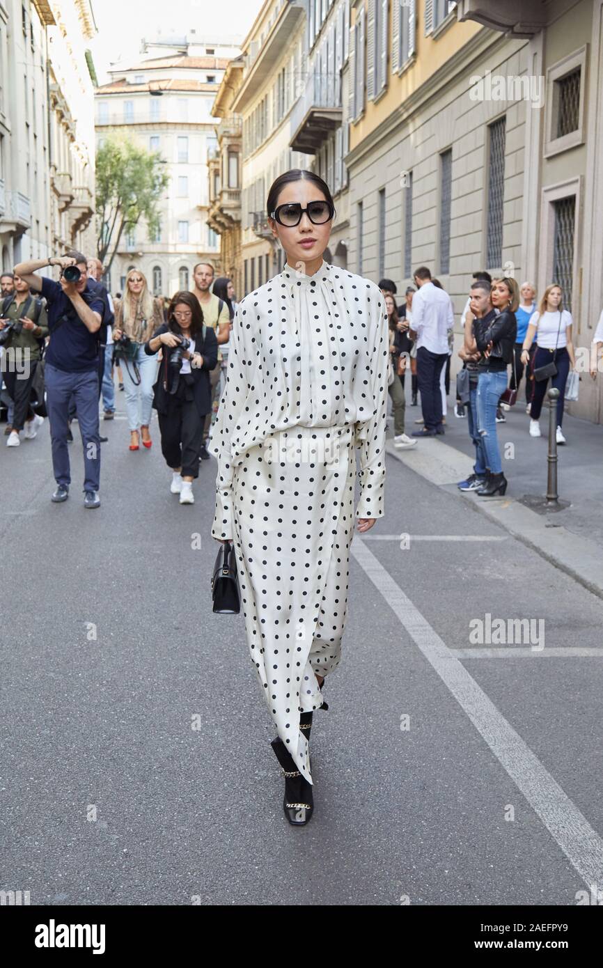 MILAN, ITALY - SEPTEMBER 21, 2019: Woman with white and black polka dot dress before Giorgio Armani fashion show, Milan Fashion Week street style Stock Photo