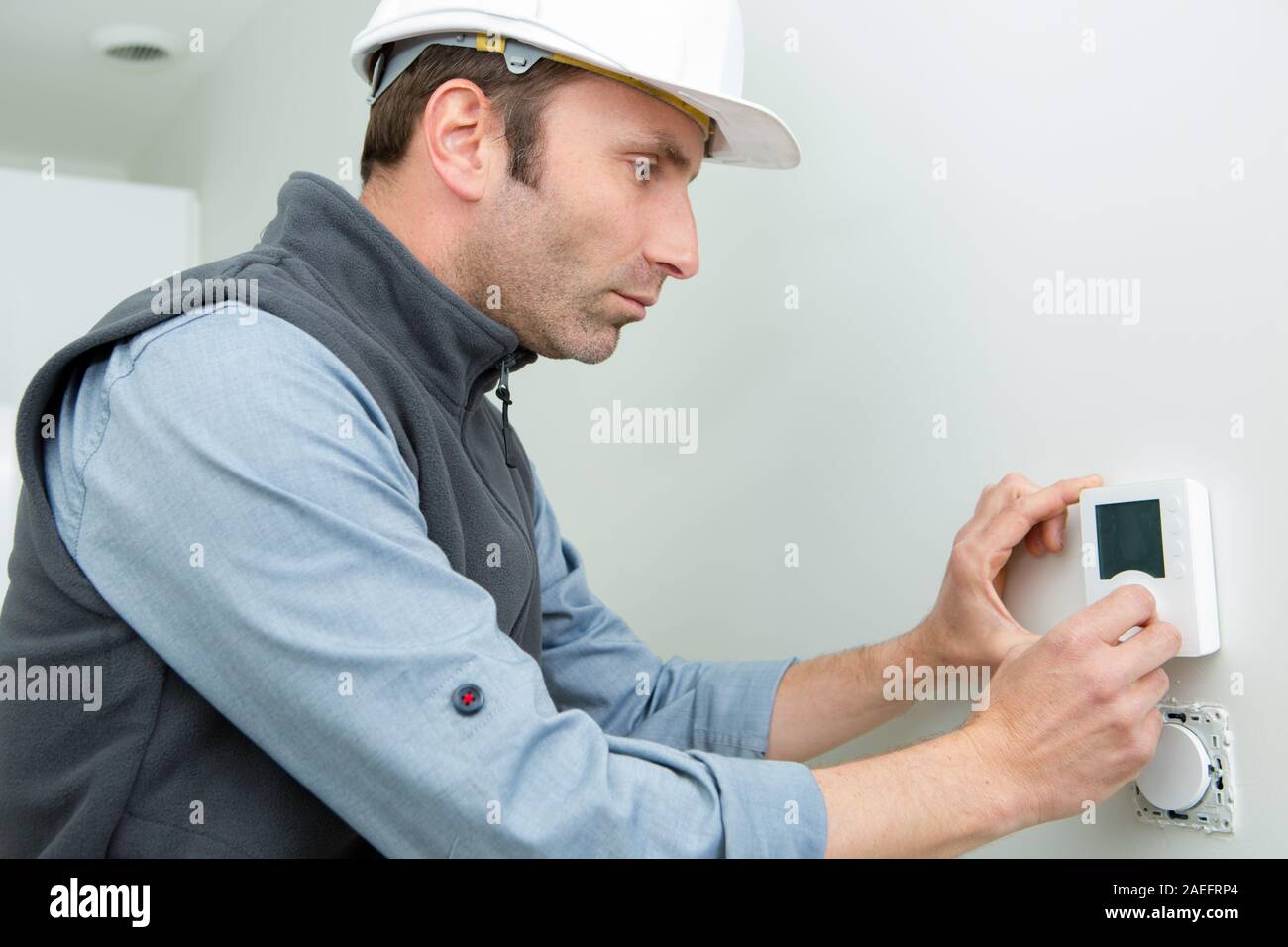 male worker installing thermostat Stock Photo