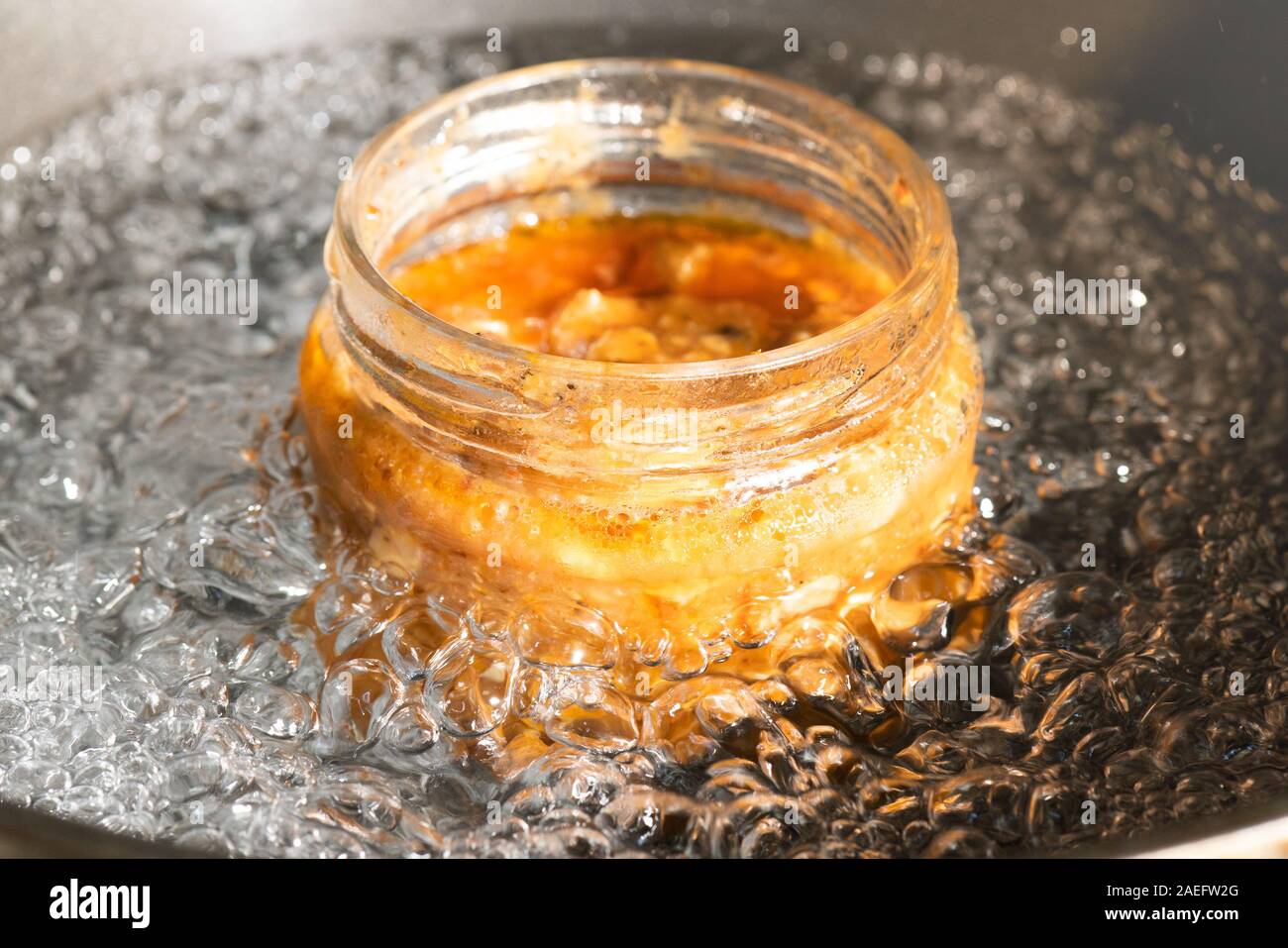 Bain-marie cooking with a food jar in middle of boiling water bath to reheat it Stock Photo