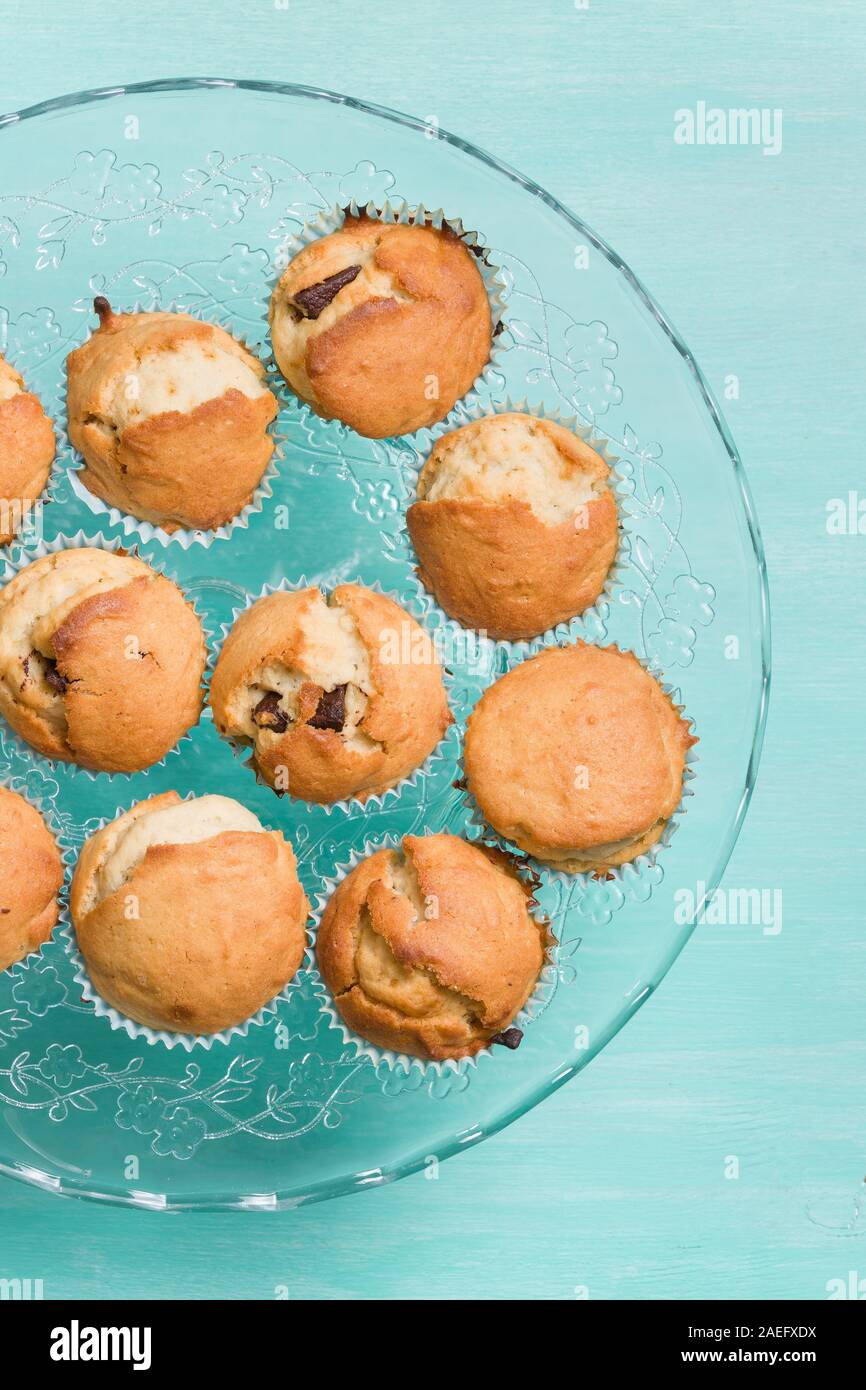 Delicious homemade vanilla muffins with chocolate on the glass plate on turquoise background. Sweet dessert for celebration, party or snack. Cupcakes. Stock Photo