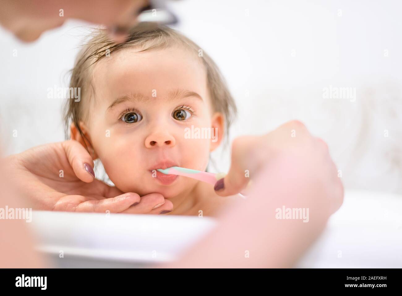 Happy 1 year old Baby in bathtubbrushing teeth in bathroom with mother