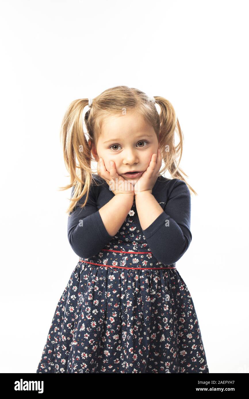 portrait of a pensive blond little girl holding her face with her hands. Stock Photo