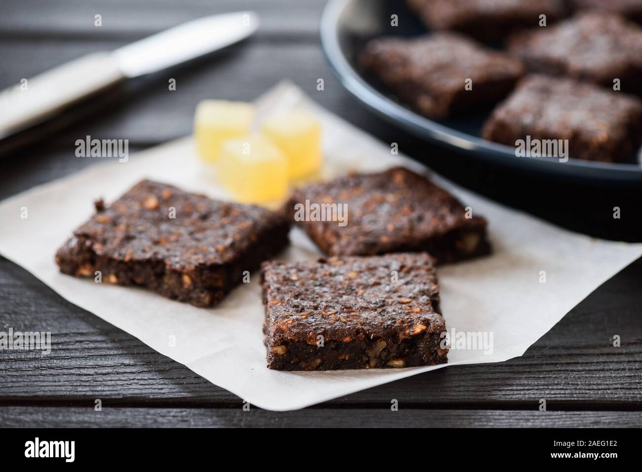 Vegan sweets. Homemade brownie pieces and jelly cubes on navy blue background closeup Stock Photo