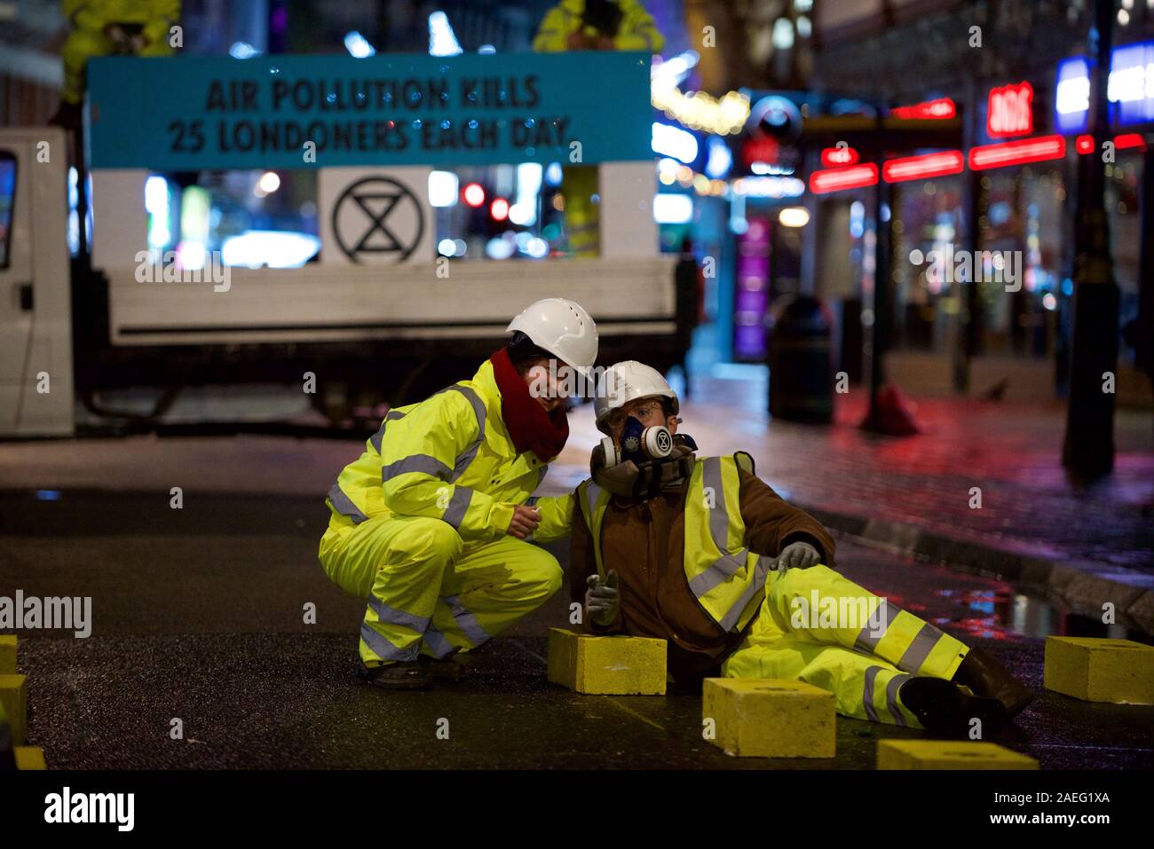 London, UK. 09th Dec, 2019. Extinction Rebellion 'Air That We Grieve' protest protester launched a pre-dawn action in Central London to protest illegal air quality levels in the capital. Dressed as highway maintenance workers, they blocked Cranbourne St and glued themselves to concrete blocks also glued to the road Credit: Gareth Morris/Alamy Live News Stock Photo