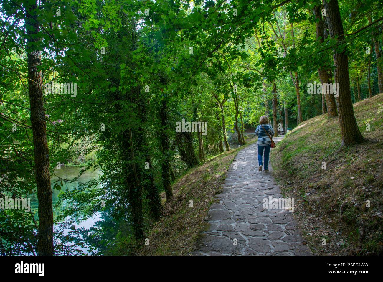 Woman walking along a river bank path. Fontibre, Cantabria, Spain. Stock Photo