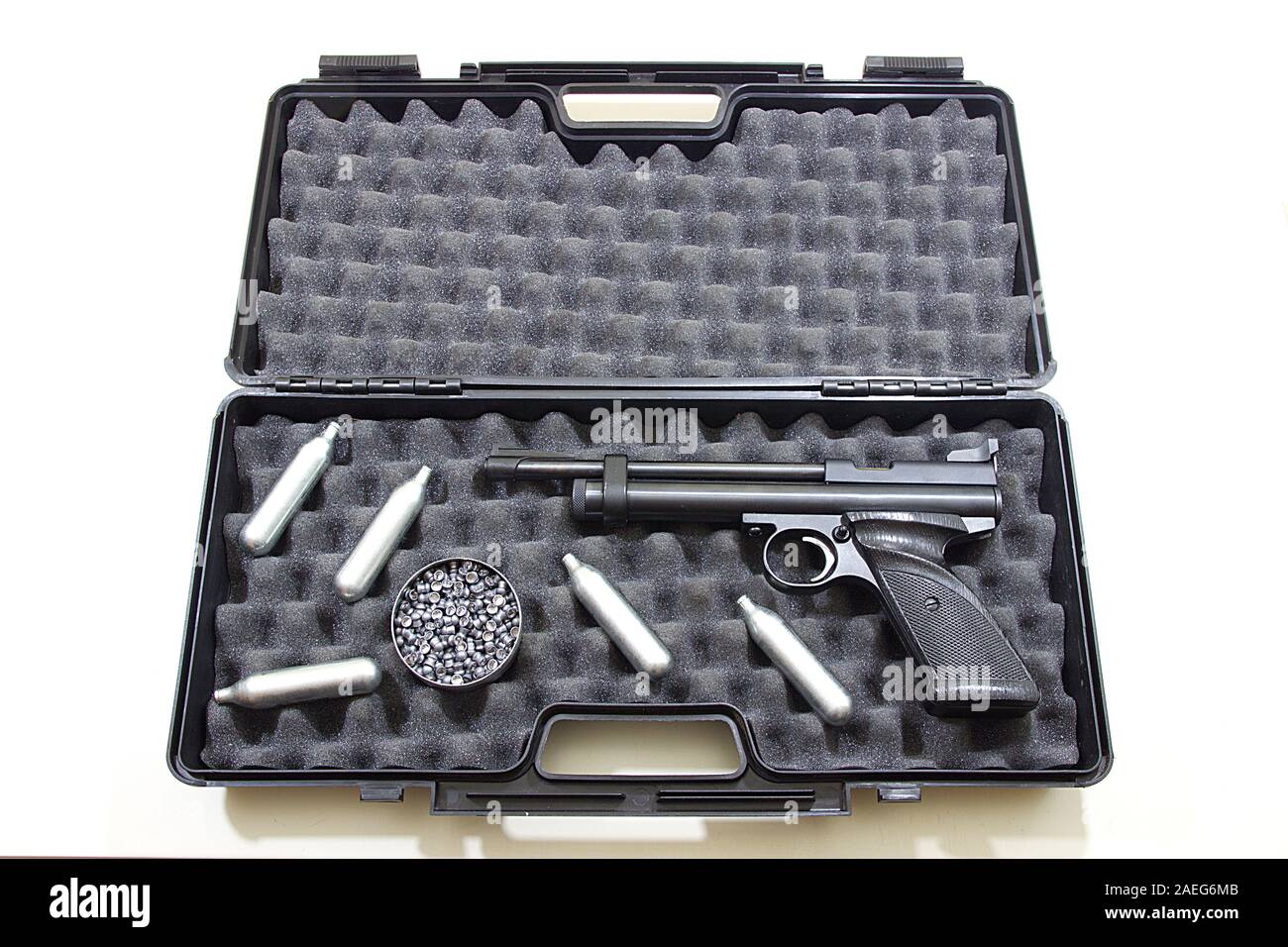 Air gun pistol in a plastic hard pistol case with round box of lead pellets and capsules of 12 grams CO2 gas. Top view, isolated on white background Stock Photo