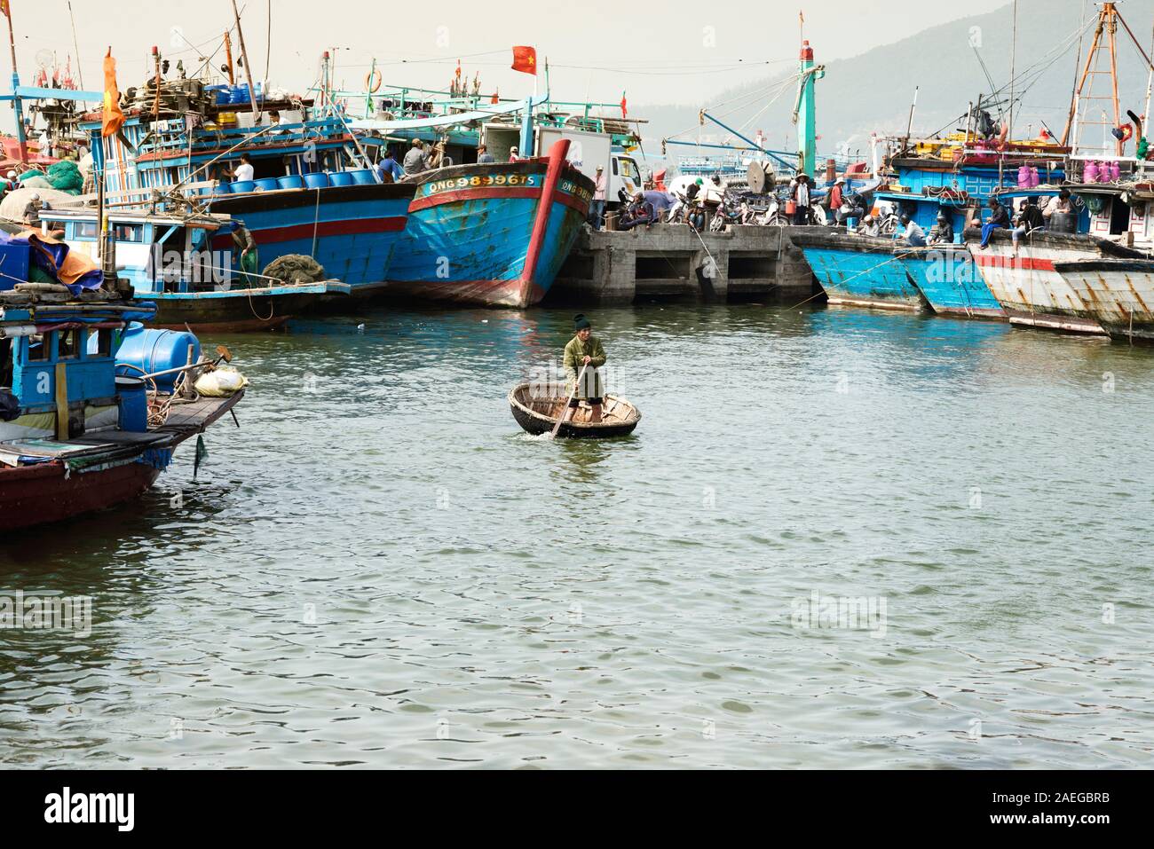 Da Nang, Vietnam - December 26: Vietnamese Man Padding Round Woven Bamboo Coracle. Fishermen On Their Boats At The Background Stock Photo