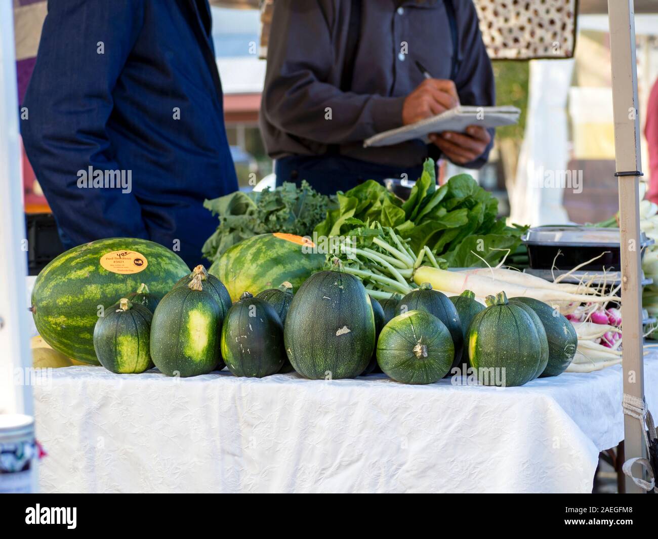 Watermelons and vegetables for sale displayed on a table at the Corpus Christi, Texas USA Southside Farmer's Market. Stock Photo