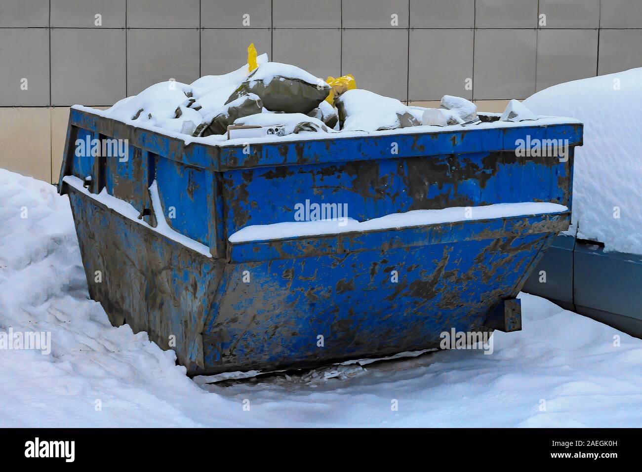 Blue industrial freight garbage bin near construction site filled with