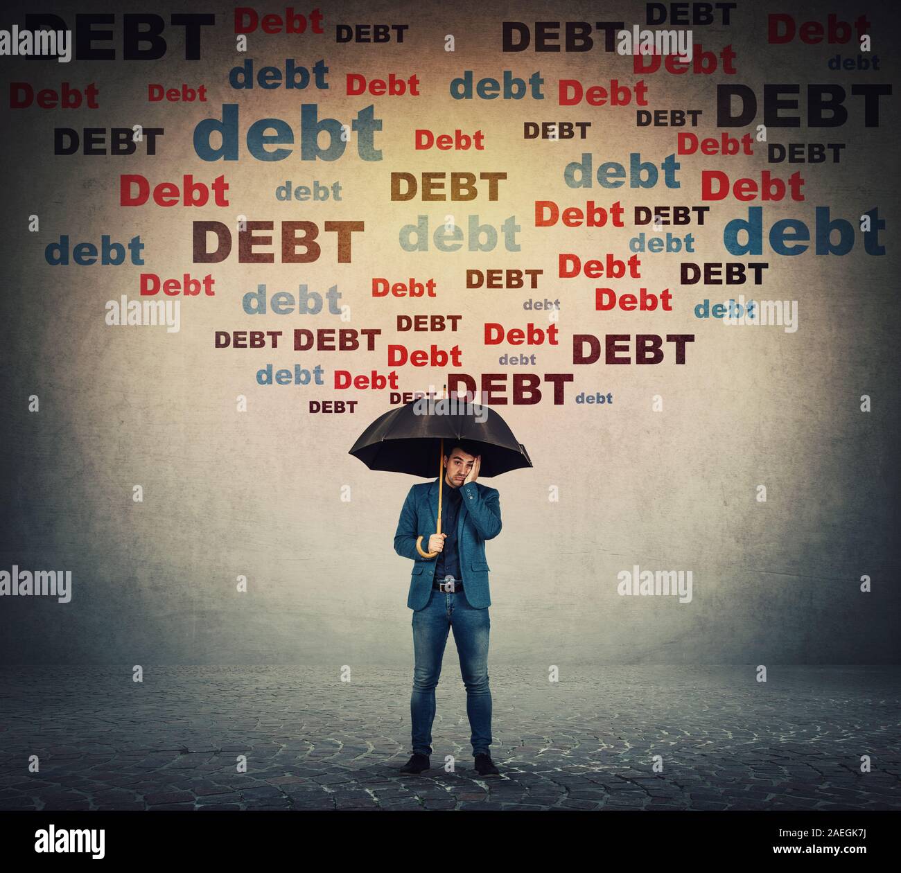 Desperate businessman hiding behind umbrella as a shield to protect of huge debt amount falling as rain and pressing him. Business concept of facing f Stock Photo