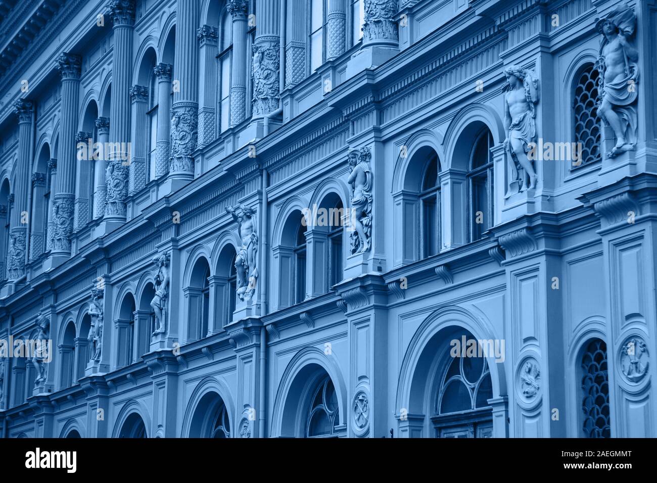 An old building with many windows in a row in a trendy classic blue style. Stock Photo