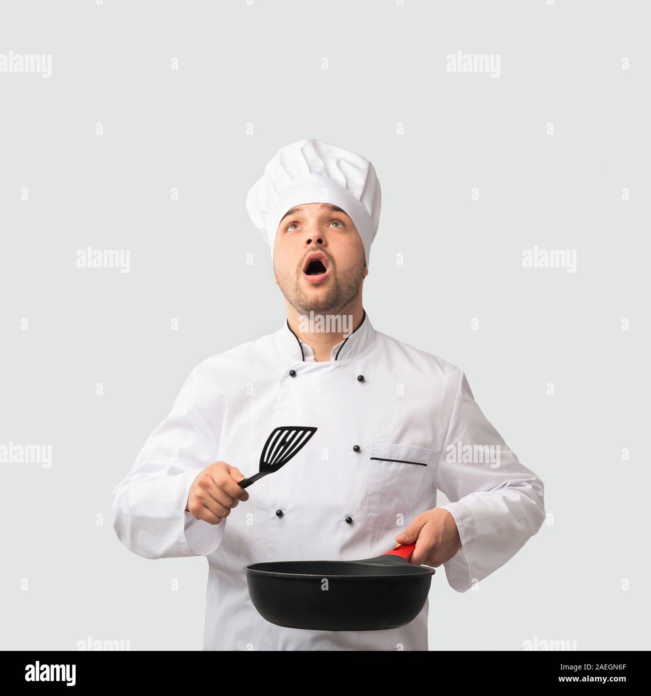 Surprised Chef Man Holding Pan Looking Up Standing, Studio Shot Stock Photo