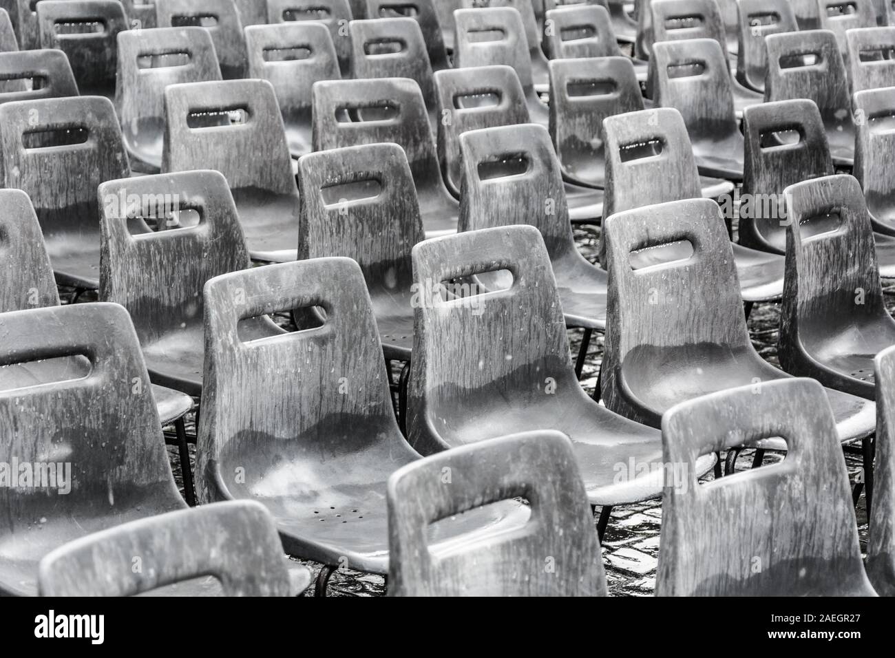 Rows of empty gray chairs in the rain, background. Stock Photo