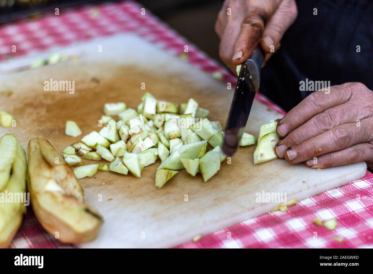 Senior woman hand cutting and chopping eggplant. Real life Stock Photo