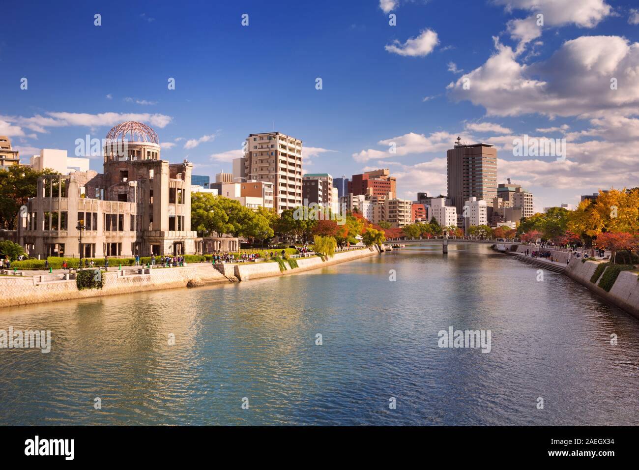 The Atomic Bomb Dome (原爆ドーム) on the left and the Peace Memorial Park on the right along the river in Hiroshima on a sunny afternoon in autumn. Stock Photo