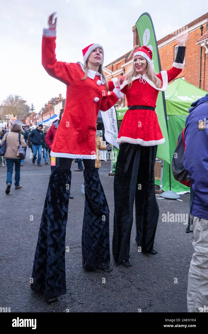 Stilt walkers dressed in santa costumes at the Farnham Christmas market 2019 in the town centre, Surrey, UK Stock Photo