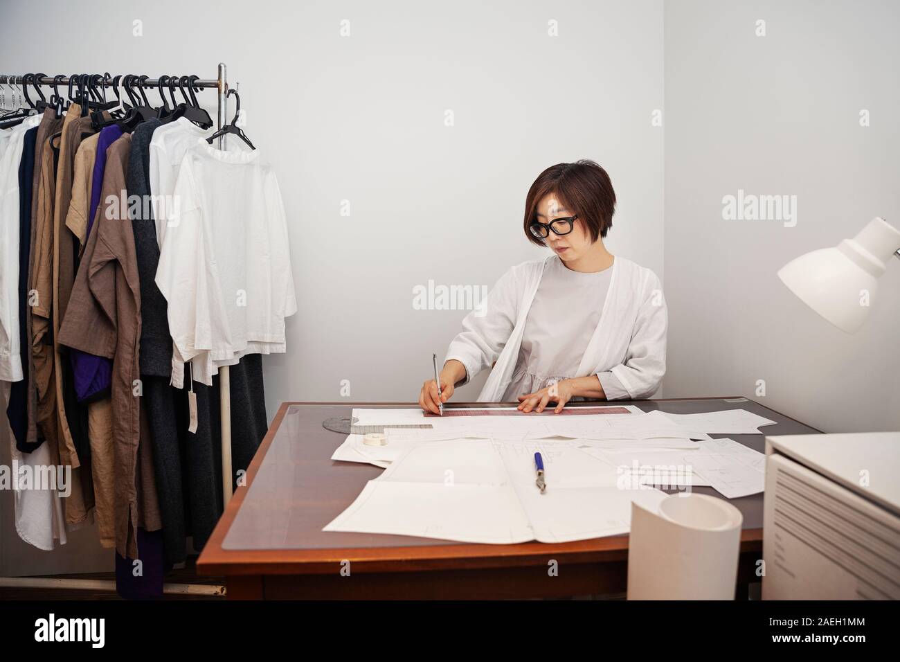 Japanese woman wearing glasses working at a desk in a small fashion boutique. Stock Photo
