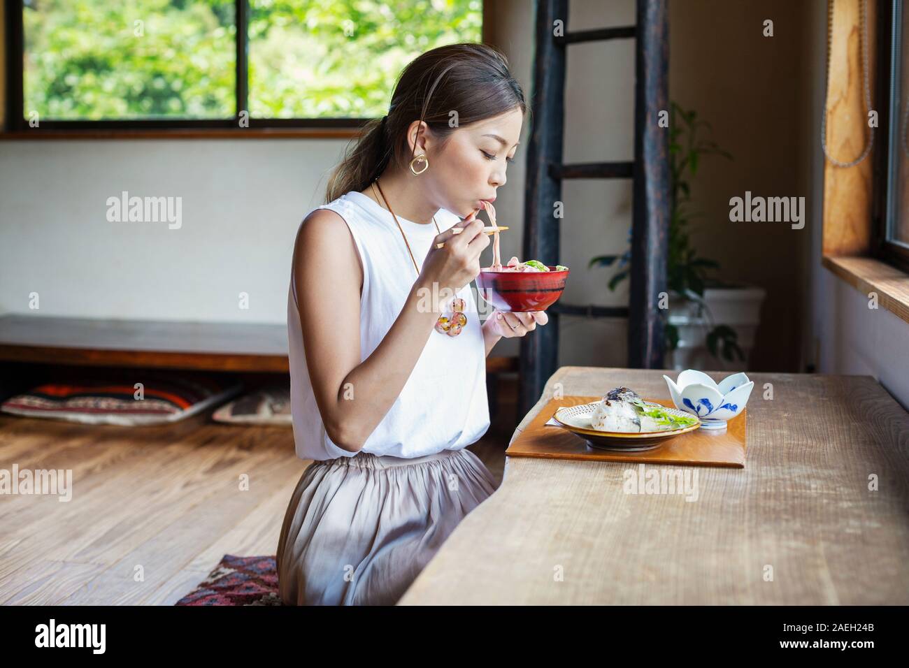 Japanese woman sitting at a table in a Japanese restaurant, eating. 