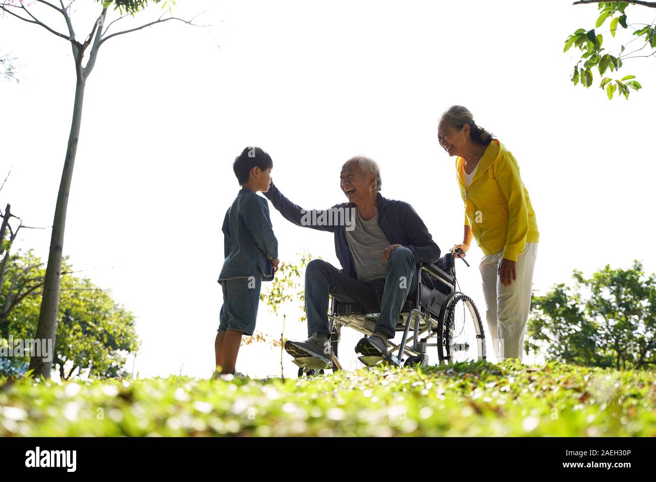 asian grandfather grandmother and grandson having fun outdoors in park Stock Photo