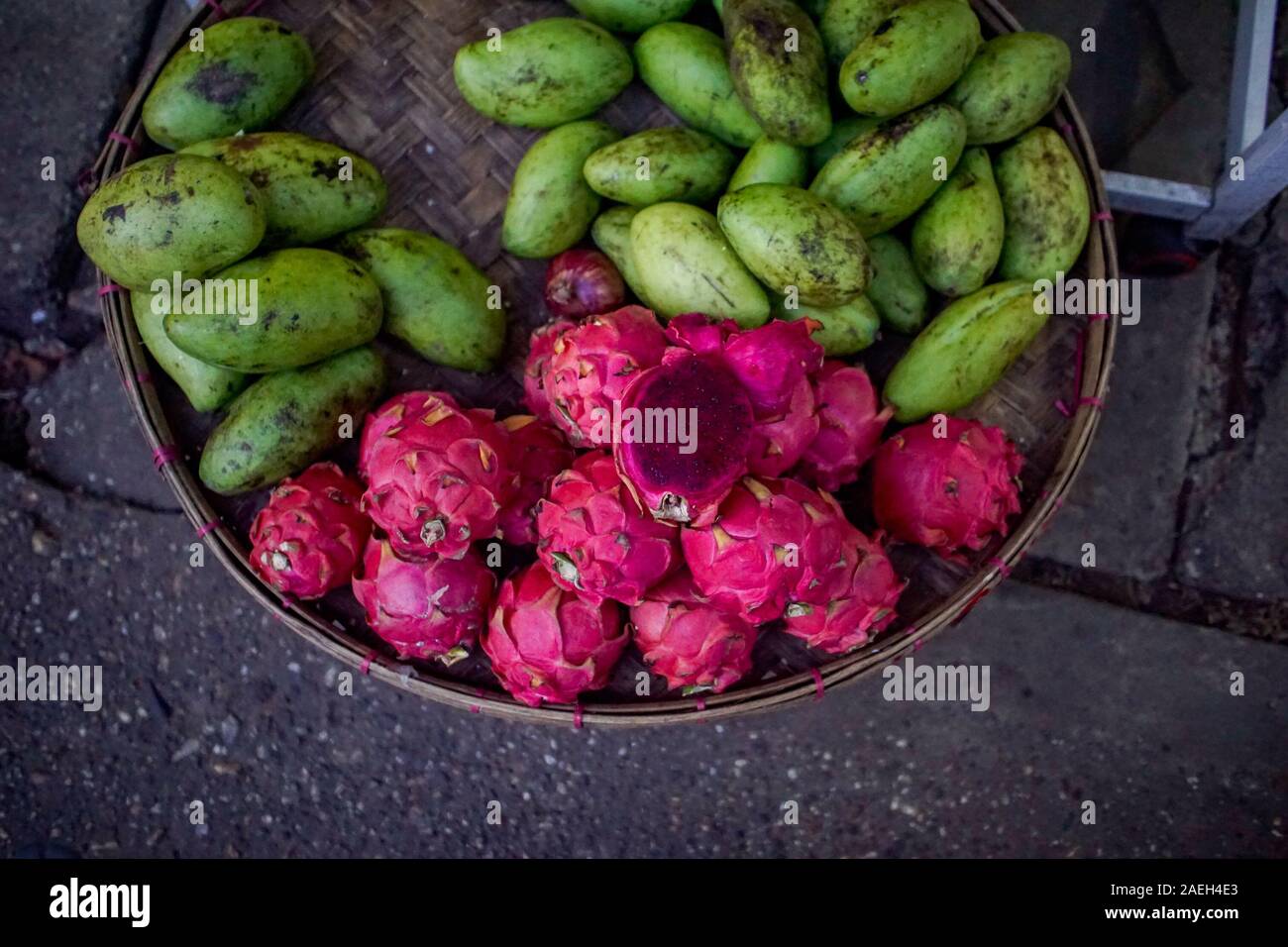 A brightly coloured platter of red dragonfruit and green mangoes for sale on the street in Yangon, formerly Rangoon, in Myanmar (Burma) Stock Photo