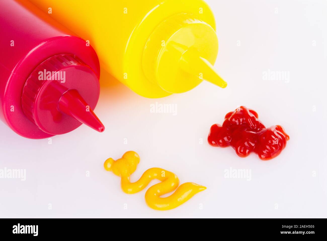 yellow plastic mustard bottle and a red plastic ketchup bottle are side by side. The condiment squirts do not match what is inside the bottles. Stock Photo