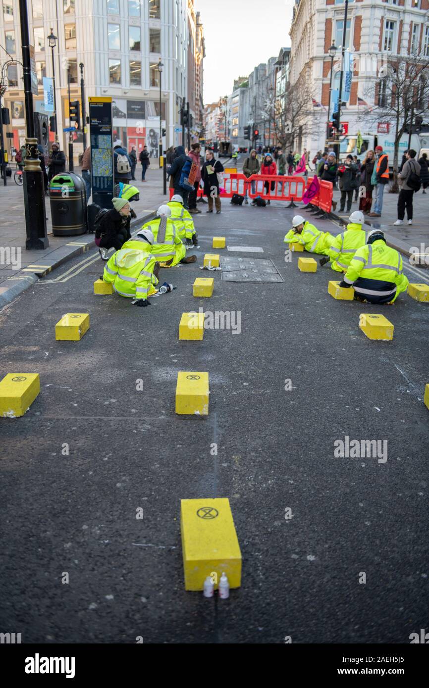 Cranbourn Street, London, UK. 9th December 2019. Extinction Rebellion protesters glue themselves onto the road in Cranbourn Street, Leicester Square, and block the road with a truck to bring attention to London’s air pollution. Credit: Malcolm Park/Alamy Live News. Stock Photo