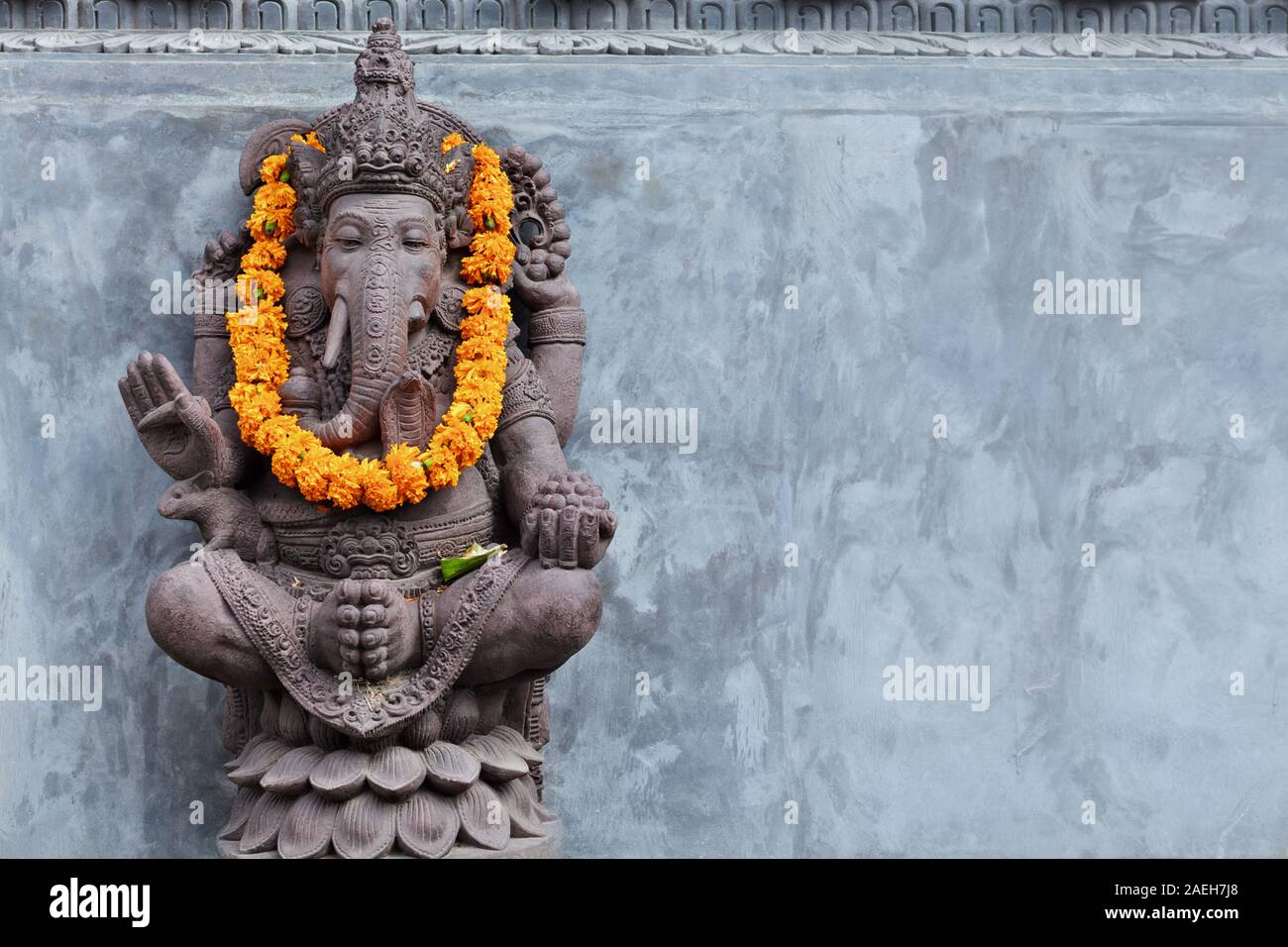 Ganesha sitting in meditating yoga pose in front of hindu temple