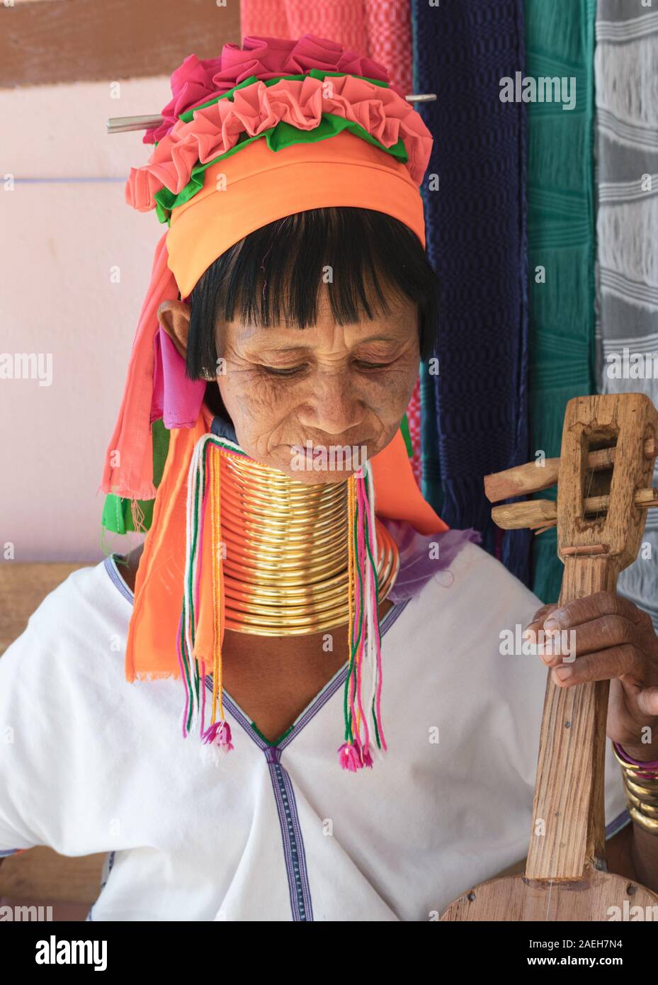 An eldery woman from Kayan tribe wearing traditional outfit and brass neck rings playing Kayan guitar with four strings in Pan Pet, Loikaw, Myanmar. Stock Photo