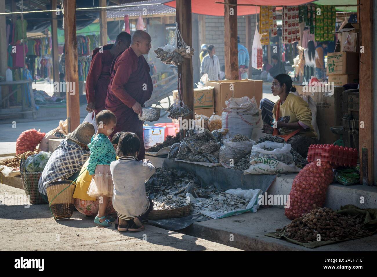 Buddhist monks collecting donation from a local shop owner at the weekly food market in Loikaw. This is common practise in Myanmar. Stock Photo