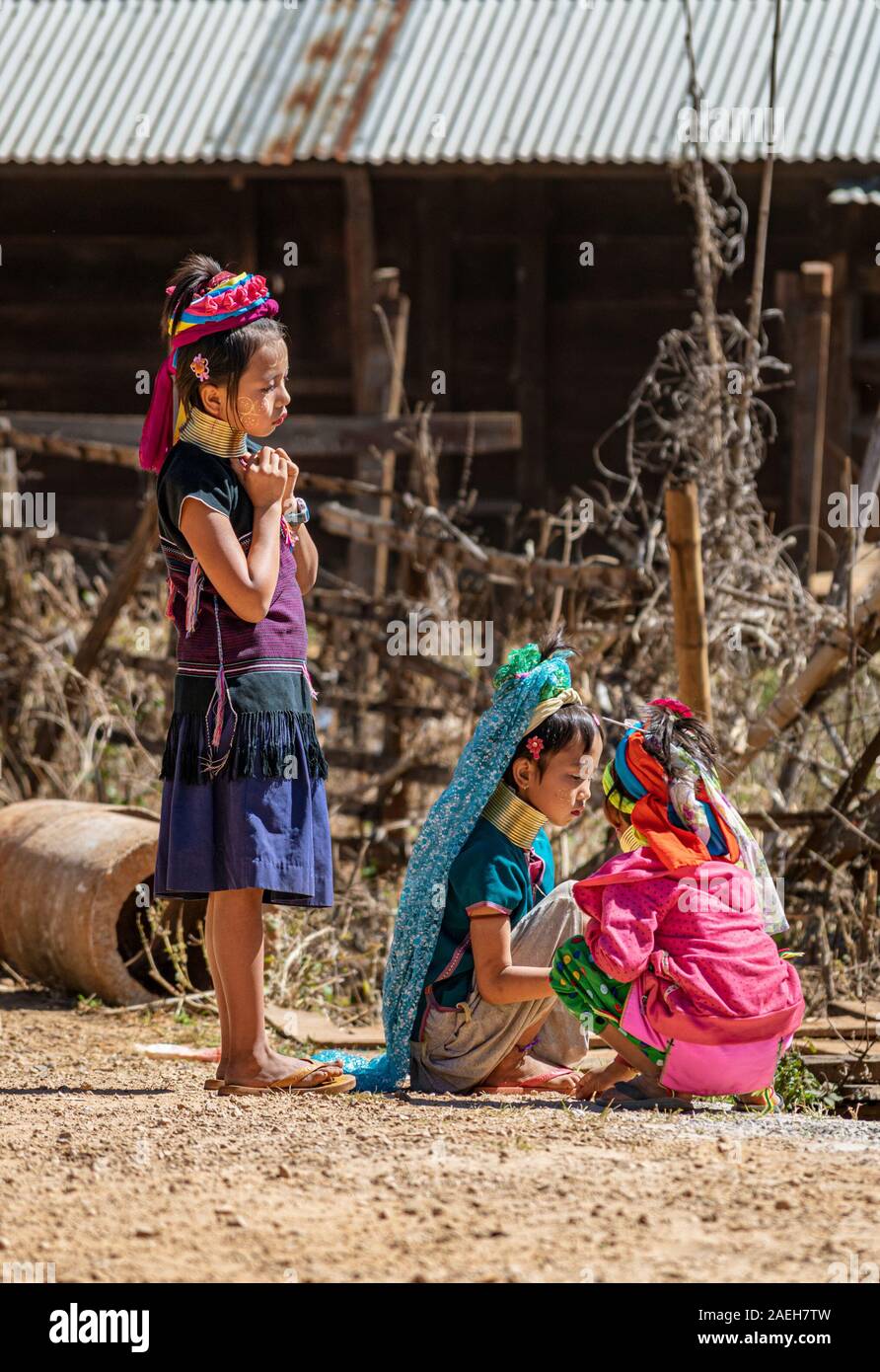 Three young girls from Kayan tribe wearing traditional colorful outfits playing on the road in Pan Pet village. Stock Photo