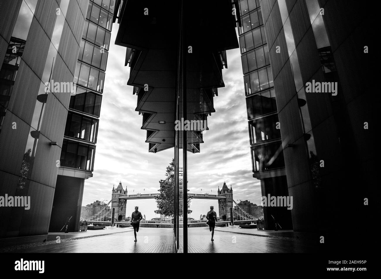 Athlete run in London between buildings, Tower Bridge in background. Black and white photo. Stock Photo