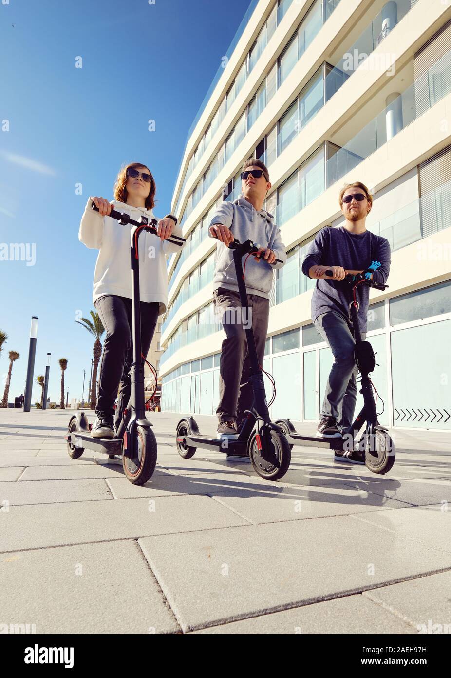 Three best friends young 20s -30s girl and guys spend time outdoors  gathered together driving on electric scooter modern land vehicle Stock  Photo - Alamy