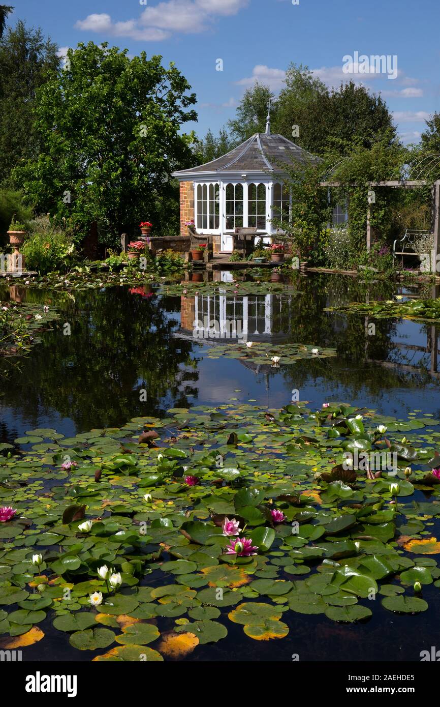 Garden summerhouse over looking ornamental pond with water lillies in english garden,England Stock Photo